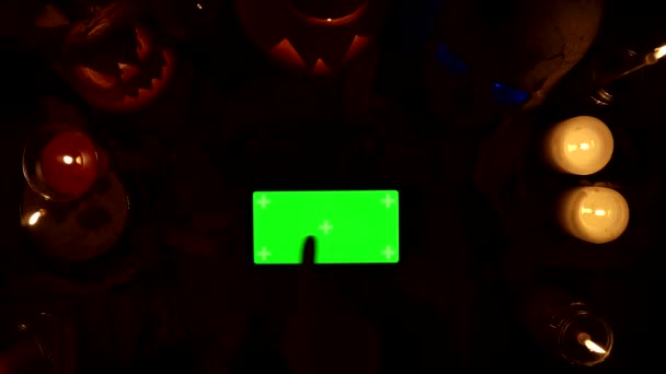 Het gebruik van smartphone met groen scherm op de achtergrond van Halloween decor 's nachts - Video