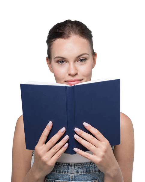 Isolated portrait of young businesswoman standing with blue book over white background. Concept of knowledge - Photo, Image