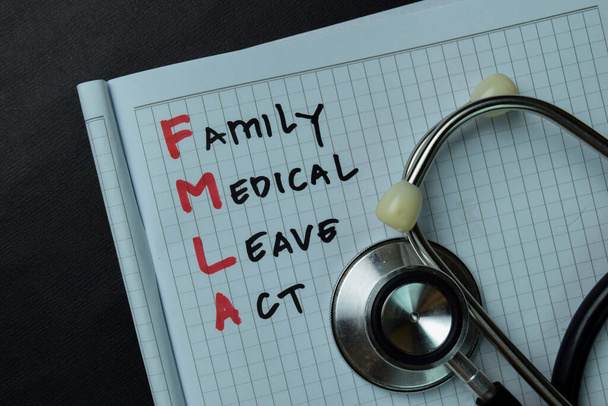 FMLA - Закон про сімейну медичну відпустку, написаний на книзі ізольований дерев'яний стіл
. - Фото, зображення