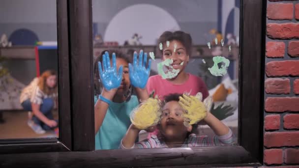 Mulatto tytöt tekevät kädenjälkiä ikkunalasiin - Materiaali, video