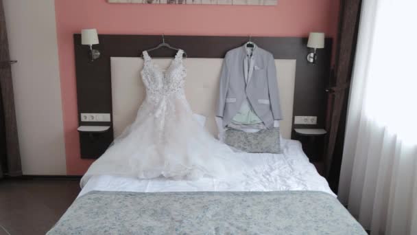 Mooie stijlvolle trouwjas en jurk op het bed. - Video