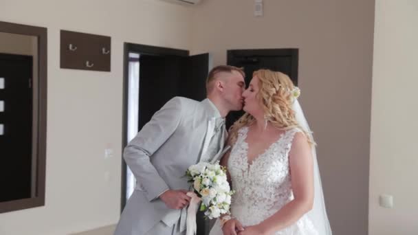 Schöner Bräutigam im Zimmer küsst die Braut. - Filmmaterial, Video