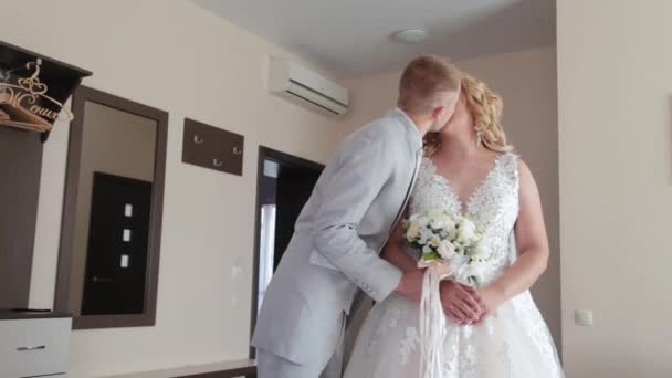 Schöner Bräutigam im Zimmer küsst die Braut. - Filmmaterial, Video