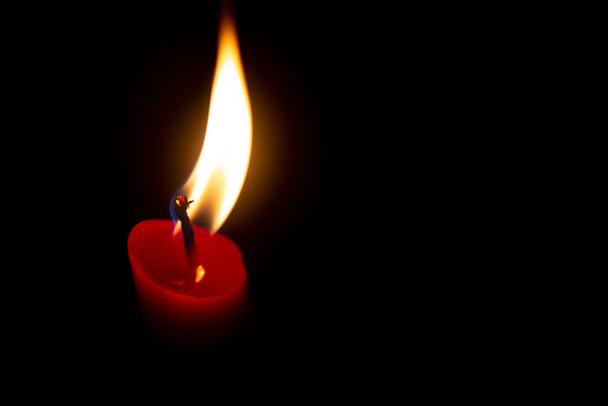 Red candle with yellow flame on black background - Photo, Image