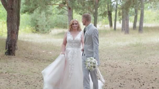 Nagyon szép menyasszony és vőlegény sétálnak az erdőben nyáron.. - Felvétel, videó