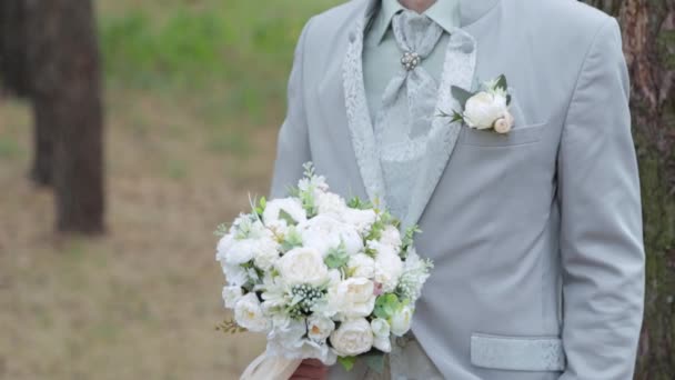 Handsome groom in the woods by the tree with boutonniere. - Footage, Video