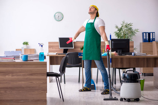 Jonge mannelijke aannemer schoonmaken van het kantoor - Foto, afbeelding