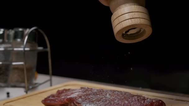 Close-up van de handen van een chef-kok peper malen met een handpepermolen. Langzame beweging - Video