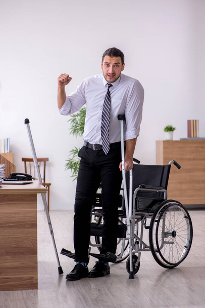 Νεαρός εργαζόμενος με αναπηρία που υποφέρει στο χώρο εργασίας - Φωτογραφία, εικόνα