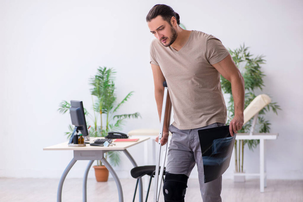 Young leg injured man with crutches looking x-ray - Φωτογραφία, εικόνα