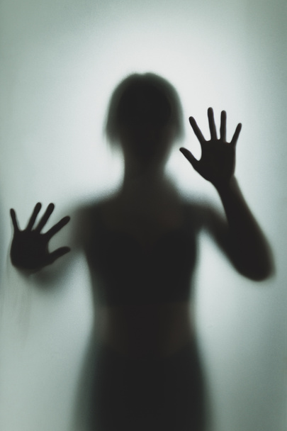 Fantasma concepto sombra de una mujer detrás de la mano borrosa de vidrio mate y el cuerpo enfoque suave - Foto, Imagen