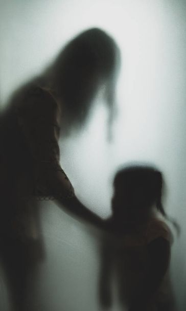 Concept fantôme ombre de la mère qui étrangle le cou de l'enfant derrière la main floue en verre mat et le corps soft focus - Photo, image