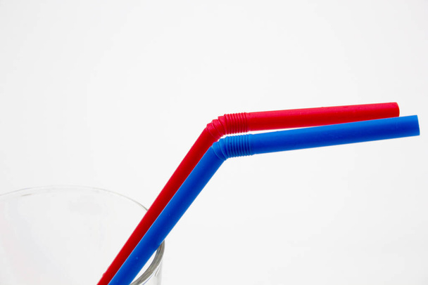 A closeup shot of red and blue straws in a transparent glass on a white background - Photo, Image