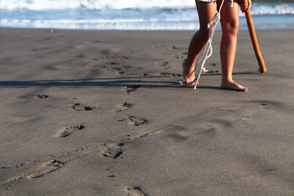 Жінка залишає ногу друкувати на мокрій піску біля морського узбережжя
 - Фото, зображення