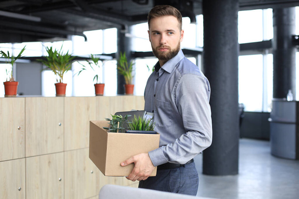 Sad dismissed worker is taking his office supplies with him from office - Photo, image