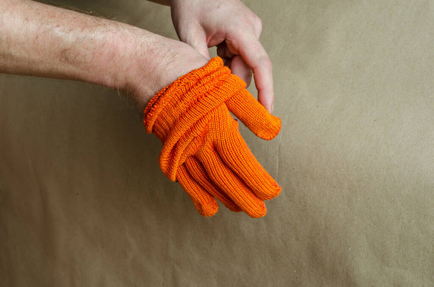 The man takes off his orange work gloves. End of the working day. Selective focus. - Photo, Image
