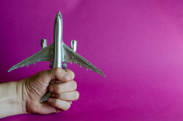 手は銀飛行機の模型を持っている。男性の手は飛行機をしっかりと握っている。飛行機のハイジャックの概念。国際テロとの闘い。選択的焦点. - 写真・画像