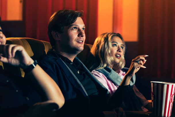 Caucasian lover and woman sitting next to them enjoying to watch movie - Photo, Image