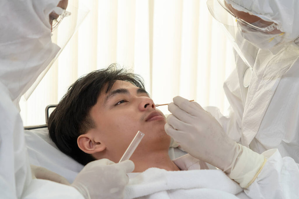 Ο γιατρός λαμβάνει Nasopharyngeal Swab Δείγμα για να εξετάσει covid 19 ή λοίμωξη από τον ιό του στομίου από τον ασθενή. Covid-19 ιατρική εξέταση έννοια υπηρεσία προσωπικού . - Φωτογραφία, εικόνα