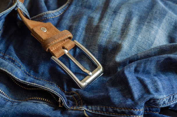 Gros plan sur un jean bleu avec une ceinture en cuir marron. Pantalon jeté avec désinvolture avec une mouche ouverte. Concentration sélective. - Photo, image