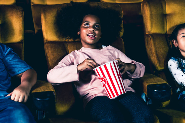Üç çocuk eğleniyor ve sinemada film izlemekten zevk alıyor. - Fotoğraf, Görsel