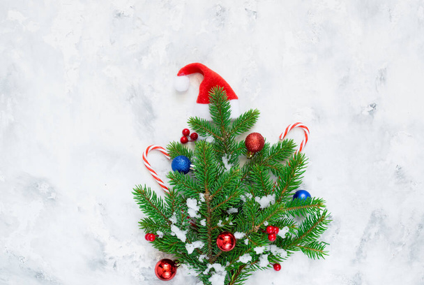 Christmas composition. Fir tree branches, snow, red Christmas balls on white concrete background. Christmas, winter, new year concept. Flat lay, top view, copy space - Foto, Bild