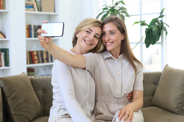 Happy middle aged mother and daughter taking selfie at home - Fotografie, Obrázek