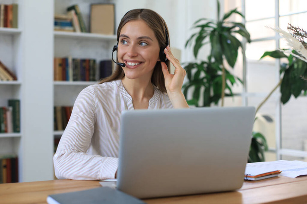 Female customer support operator with headset and smiling - Foto, afbeelding