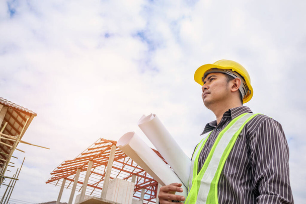 Empresário asiático engenheiro de construção trabalhador em capacete de proteção e papel plantas na mão em casa local de construção - Foto, Imagem