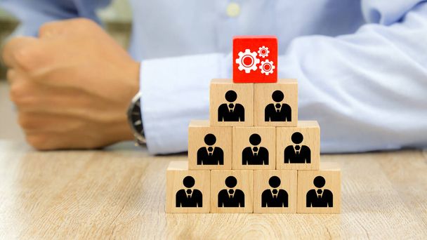 Cog with people icon on cube wooden toy blocks stacked in a pyramid shape concepts of human resources for business team organizations and leadership. - Photo, Image