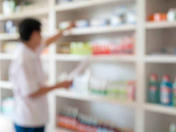 blur image of pharmacist taking medicine from shelf in the pharmacy - Photo, Image
