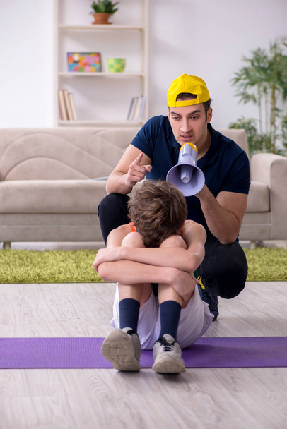 Πατέρας και γιος κάνουν αθλητικές ασκήσεις σε εσωτερικούς χώρους - Φωτογραφία, εικόνα