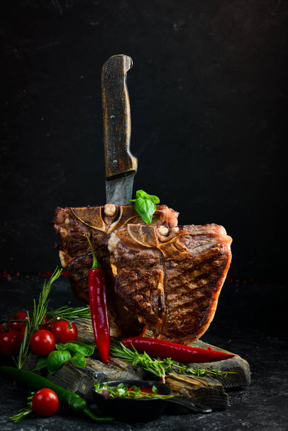 Two juicy grilled steaks with spices and herbs on a black background. Top view. Rustic style. - Fotó, kép