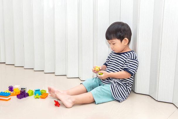 little boy  sitting on the floor playing with colorful toys at home - Foto, Imagem