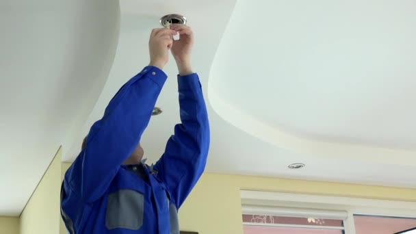 sähköasentaja mies vaihtaa LED-lamppu kattoon huoneessa. 4K - Materiaali, video