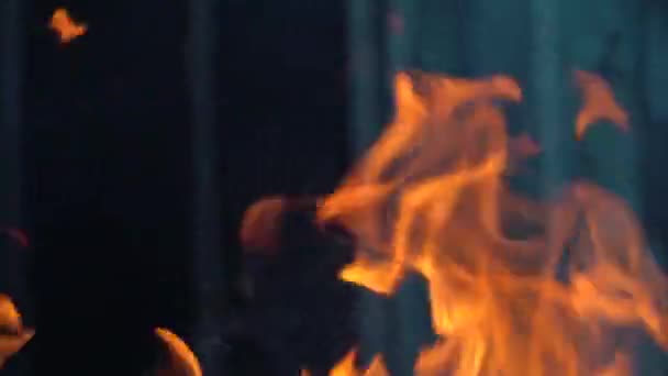 Slow-motion video van vuur en vlammen.Een vuurkorf, brandend gas of benzine brandt met vuur en vlammen.Vlammen en brandende vonken close-up, vuurpatronen.Een helse gloed van vuur in het donker met kopieerruimte - Video