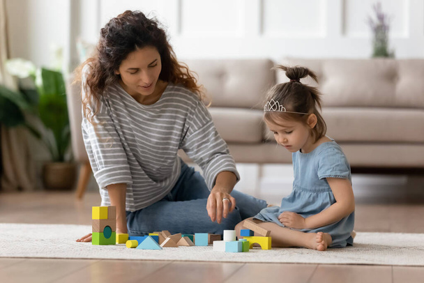 Mom and daughter play with toy blocks sit on floor - Фото, зображення