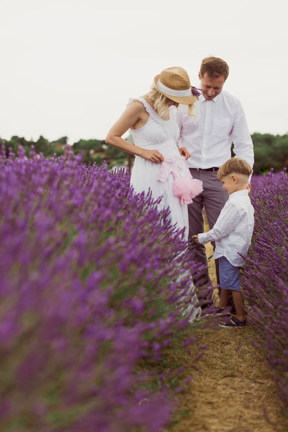 The joyful parents with a cute kid and newborn are standing in the lavender field - Foto, Imagem