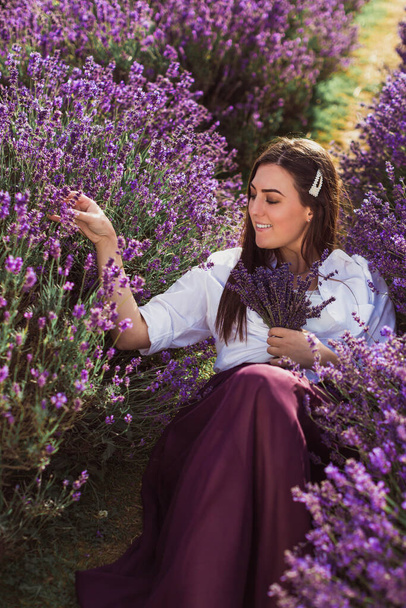 The cheerful young brunette who is lying in the lavender field - Foto, imagen