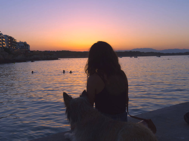 σιλουέτα μιας νεαρής γυναίκας με το σκύλο της στην Κόστα Μπράβα - Φωτογραφία, εικόνα