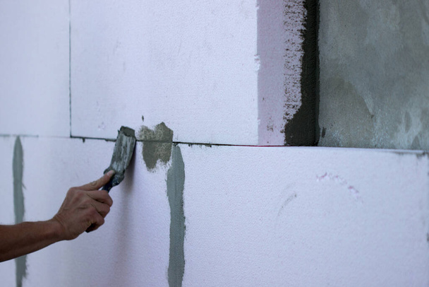 Aislamiento mural con paneles de poliestireno, aplicación de pegamento e instalación. - Foto, Imagen