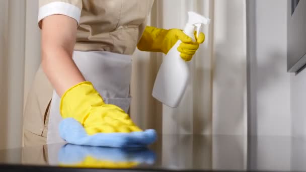 Schoonmaken in het hotel. Close-up shot van jonge vrouw huishoudster in schort reinigen, afvegen tafeloppervlak met microvezel doek, blauwe doek, Schoonmaakster zorgvuldig vegen oppervlak van houten tafel. 4 k video - Video