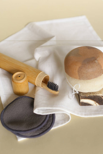 Natuurlijke eco tandenborstel, handgemaakte zeep, herbruikbare bamboe make-up remover pads en spons op witte handdoek. - Foto, afbeelding