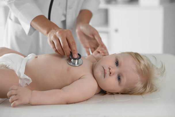 Pediatrician examining baby with stethoscope in hospital. Health care - Фото, изображение