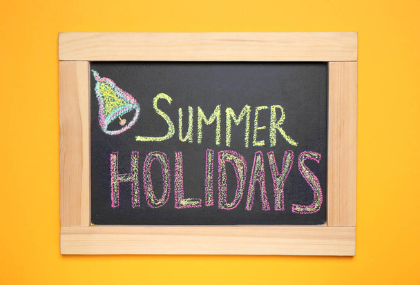 Chalkboard with phrase SUMMER HOLIDAYS on orange background, top view. School's out - Foto, Bild
