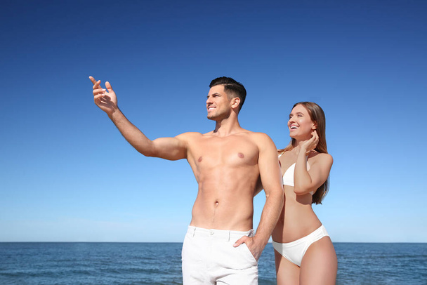 Woman in bikini and her boyfriend on beach. Happy couple - Fotó, kép