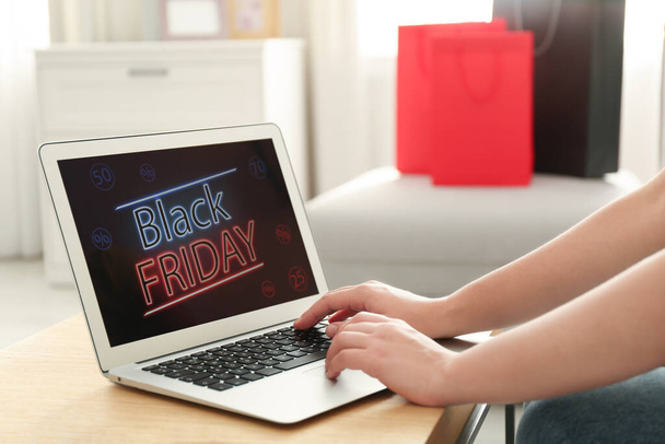 Woman using laptop with Black Friday announcement on screen at table, closeup - Fotoğraf, Görsel