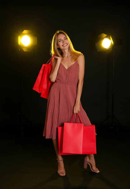 Happy young woman with shopping bags on dark background. Black Friday Sale - Fotoğraf, Görsel