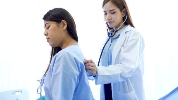 Las mujeres asiáticas que usan estetoscopio escuchan la frecuencia respiratoria de los diagnósticos pulmonares analizan al paciente en la clínica de tratamiento médico hospitalario para la terapia médica contra el cáncer de pecho usando una computadora portátil. - Imágenes, Vídeo