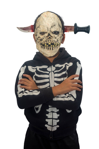 ragazzo che indossa una spaventosa maschera cranio umano Halloween con un coltello di plastica attraverso la testa. - Foto, immagini